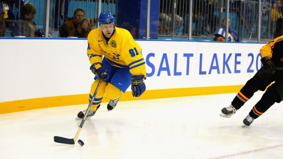 A hockey player skates with the puck.