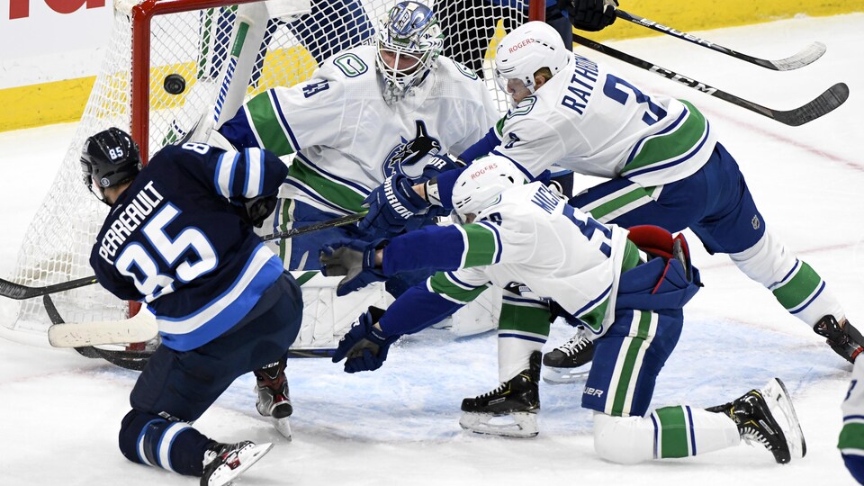 Il tire vers le filet des Canucks, protégé par le gardien Braden Holtby. Les défenseurs Marc Michaelis et Jack Rathbone plongent pour essayer de bloquer le lancer.
