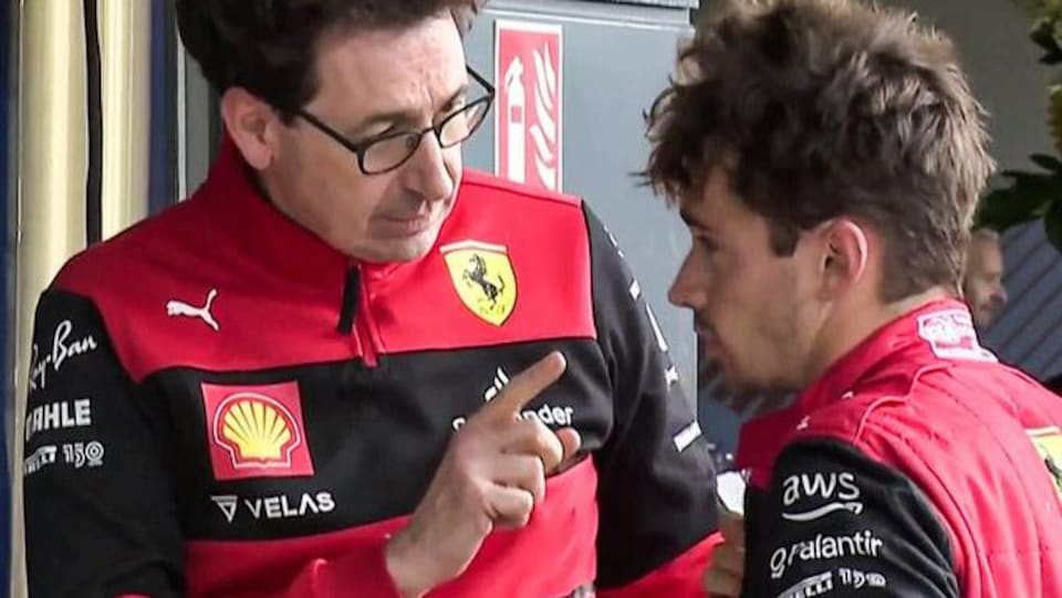 Deux hommes en uniforme de Ferrari discutent, le plus grand semble rappeler l'autre à l'ordre. 