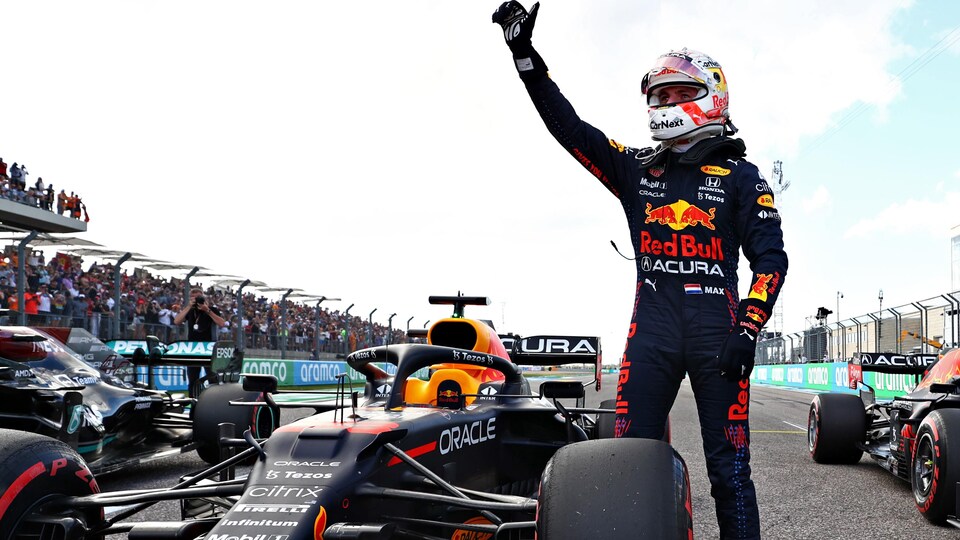 Max Verstappen salue la foule en levant la main droite.