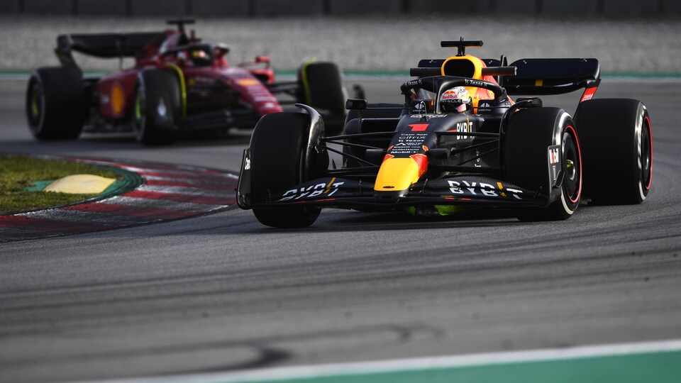 Deux pilotes se suivent sur un circuit de F1 dans un virage à droite. 