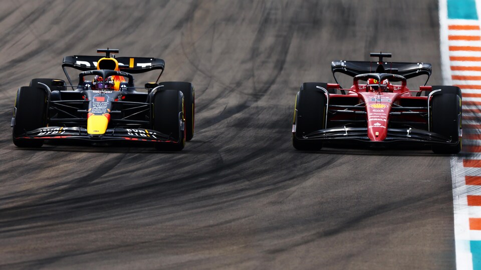Two vehicles are driving side by side on a circuit.