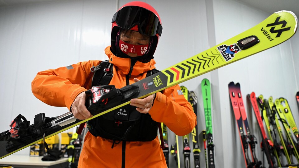 Une personne casquée vérifie son équipement de ski.
