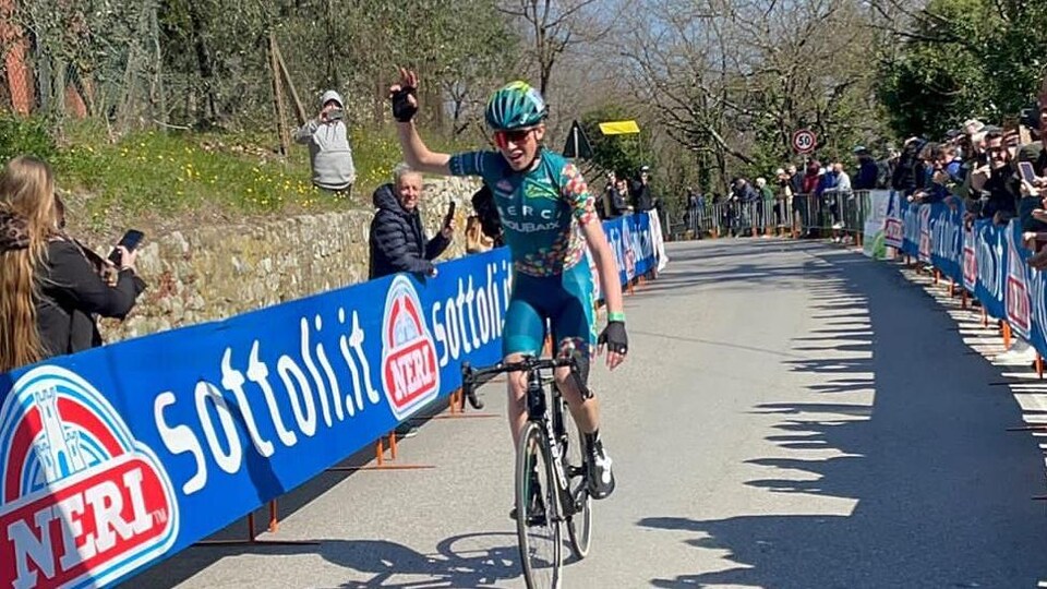 Le cycliste lève le bras en signe de victoire.