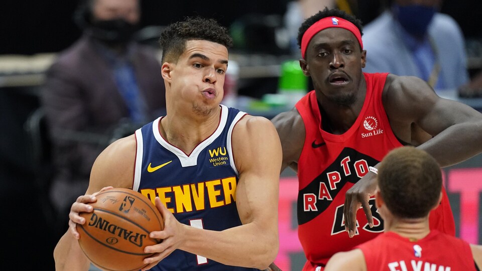 Il protège le ballon, approché par Pascal Siakam et Malachi Flynn des Raptors.