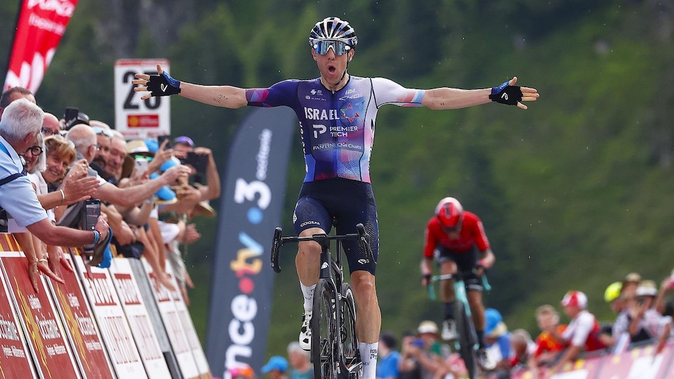 The Canadian cyclist raises his arms on his bike as he crosses the finish line.