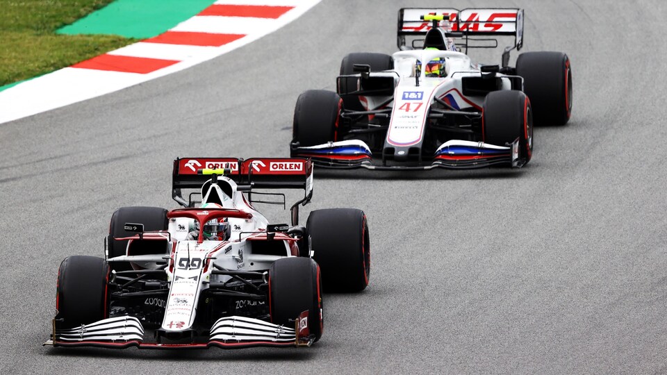 Deux monoplaces de F1 roulent l'une derrière l'autre sur un circuit. 