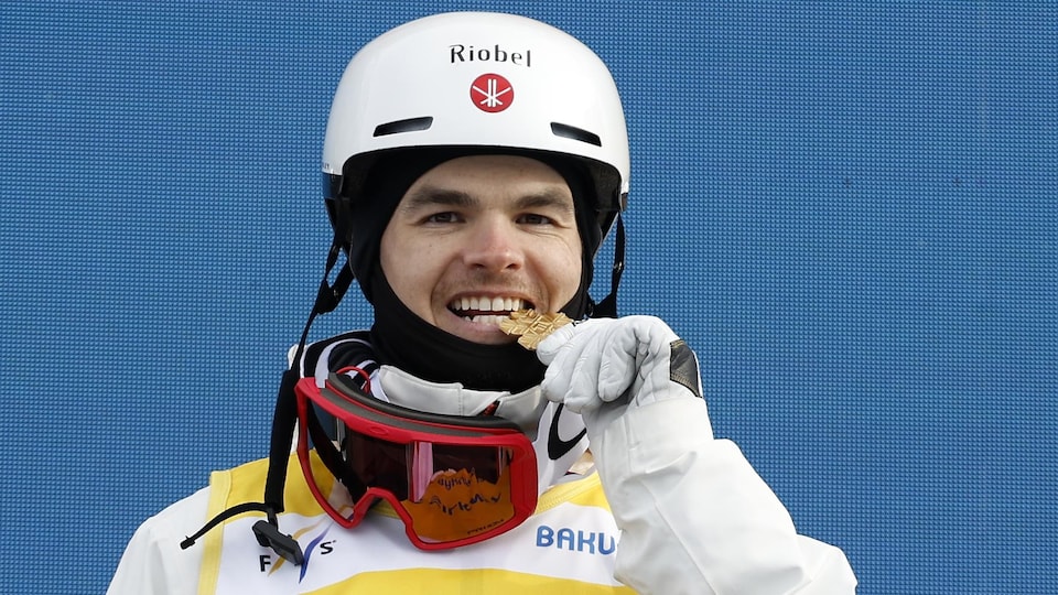 Le skieur acrobatique Mikaël Kingsbury mord sa médaille d'or.