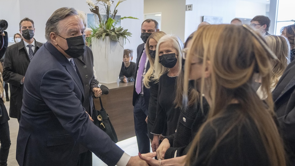 A man in a jacket shook hands with a woman dressed in black.