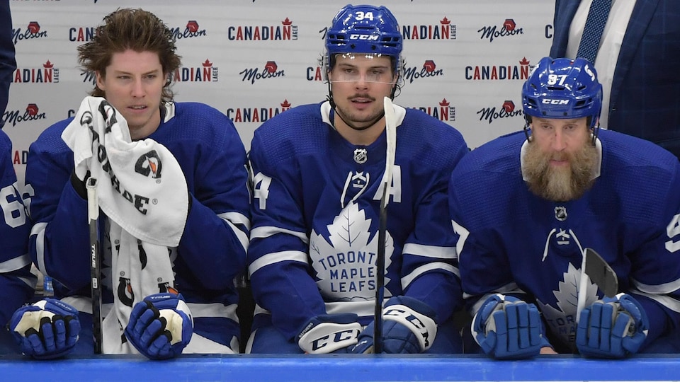 Les trois joueurs, visiblement fatigués, se reposent au banc des Maple Leafs.