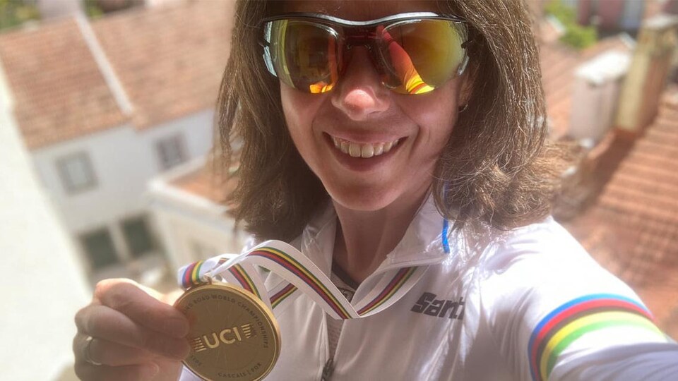 Une cycliste avec des lunettes de soleil sourit.