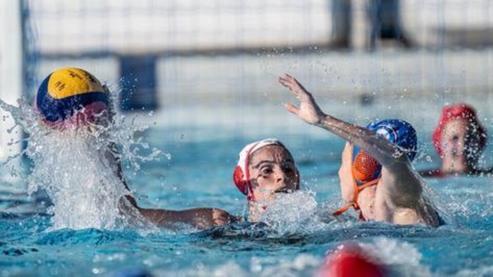 Une jeune femme effectue une feinte devant une adversaire lors d'un match de Water polo.