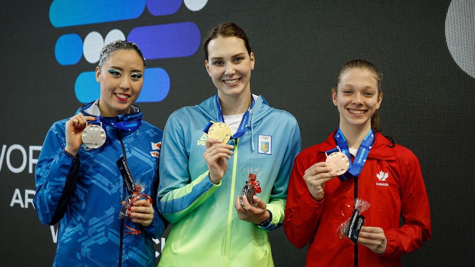 Les trois nageuses montrent leurs médailles.