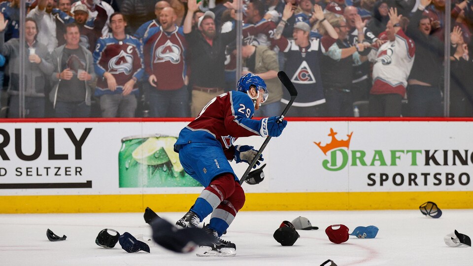 Un joueur de hockey patine à travers des casquettes lancées sur la glace. 