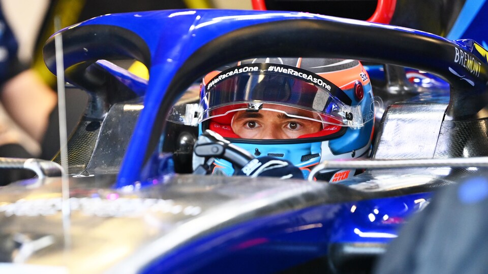 An F1 driver in his cockpit looks ahead.