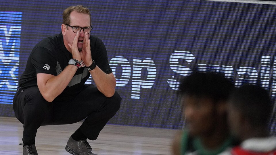 Un entraîneur de basketball crie des directives à ses joueurs.