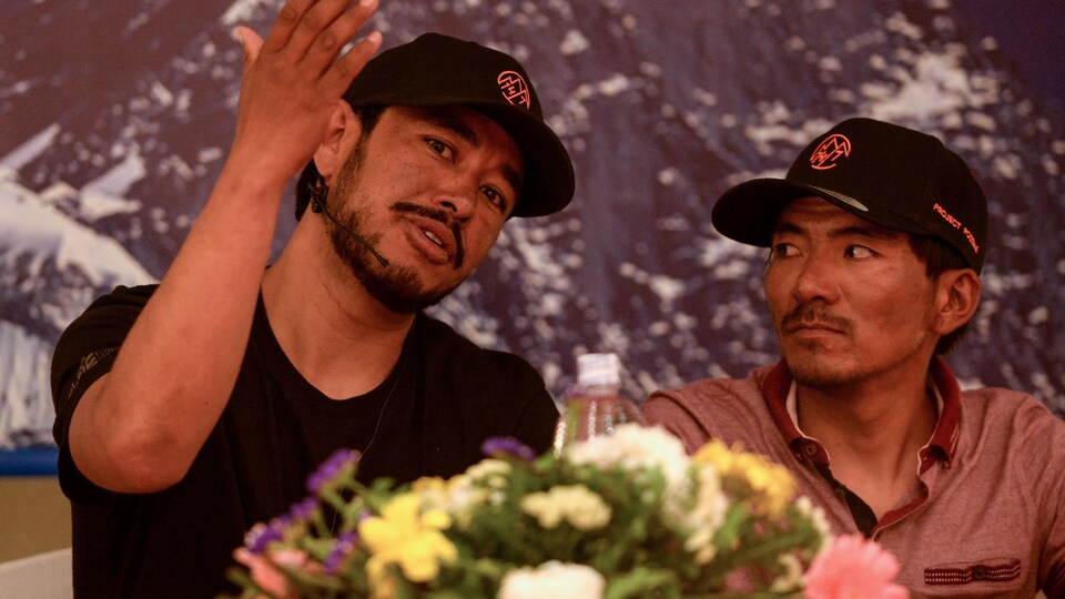 L'alpiniste Nirmal Purja lève la main pour expliquer son point sous les yeux de son sherpa Mingma David lors d'une conférence de presse