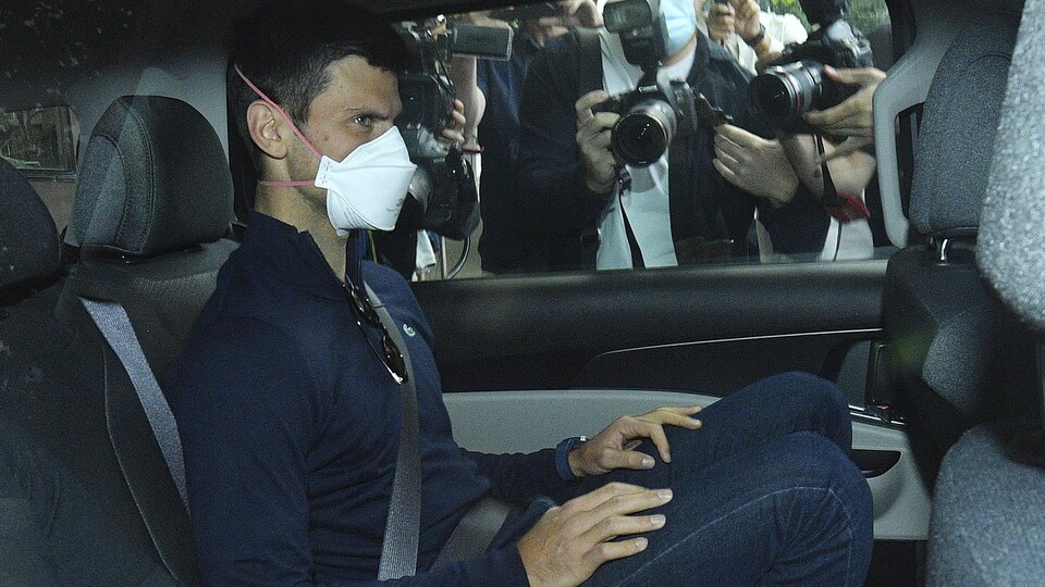 Il est assis dans une voiture, avec un masque, et des photographes le bombardent.
