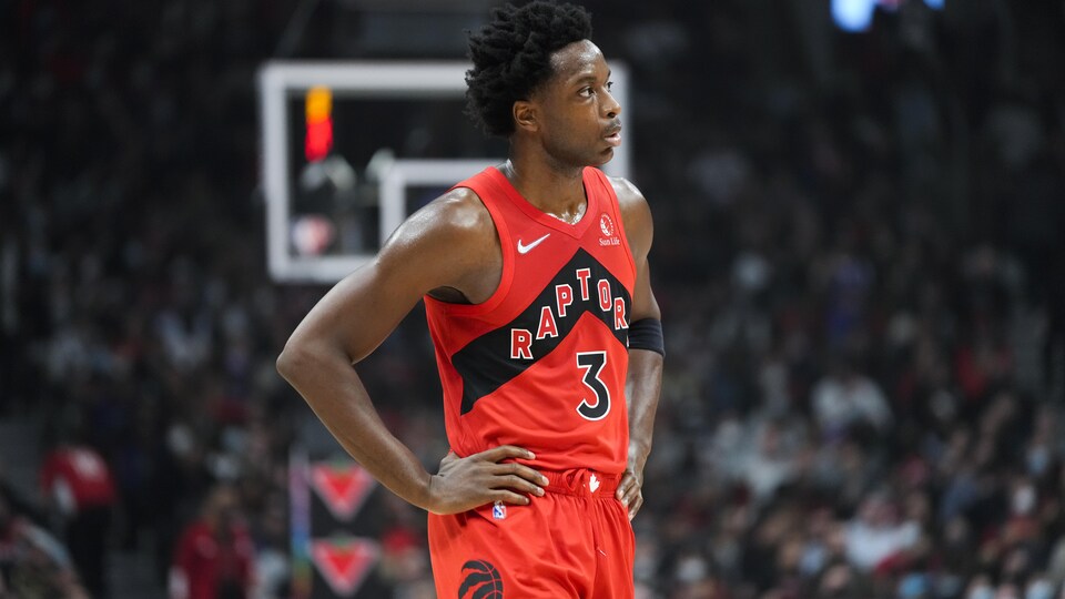Un joueur de basketball en rouge portent ses mains à ses hanches.