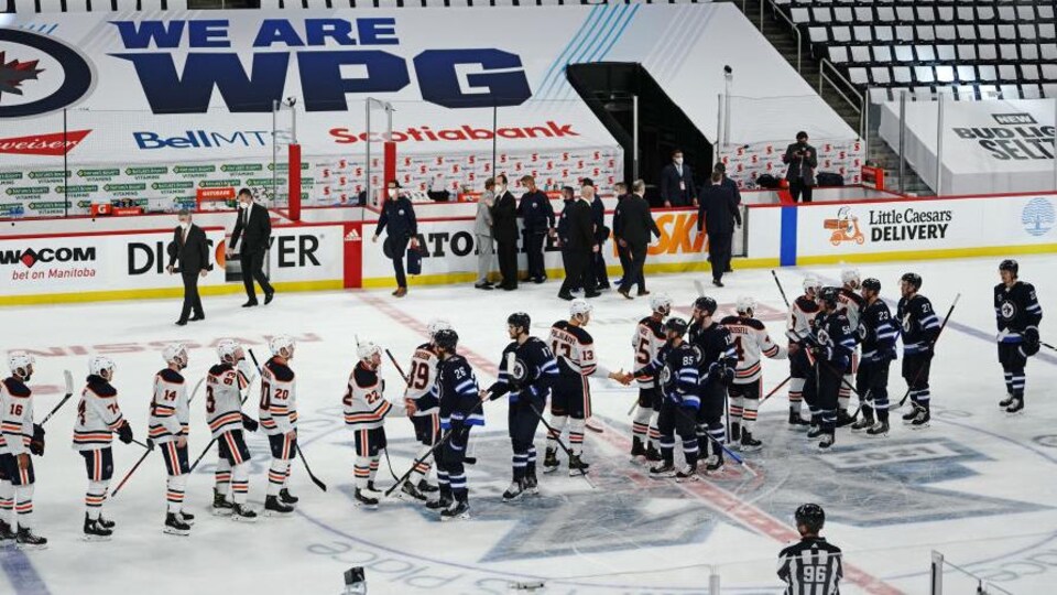 Les joueurs des Oilers et des Jets se donnent la main au centre de la patinoire.