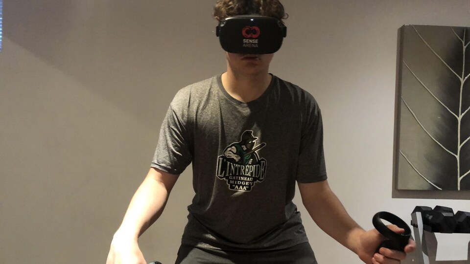 Un jeune gardien de hockey a des manettes dans les mains pour s'entraîner avec un outil de réalité virtuelle.