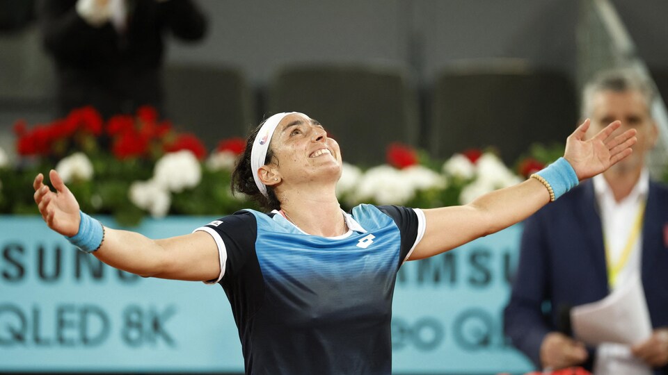 La joueuse de tennis ouvre les bras et lève les yeux au ciel après sa victoire. 