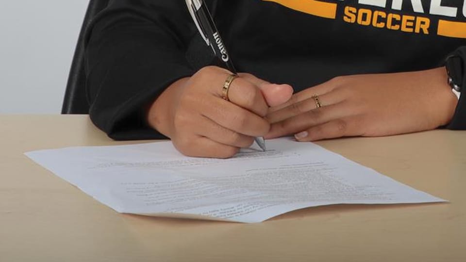 Une joueuse de soccer signe un contrat.