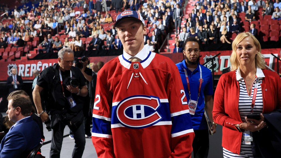 Un jeune homme est vêtu d'une casquette et d'un gilet avec le logo du Canadien de Montréal.