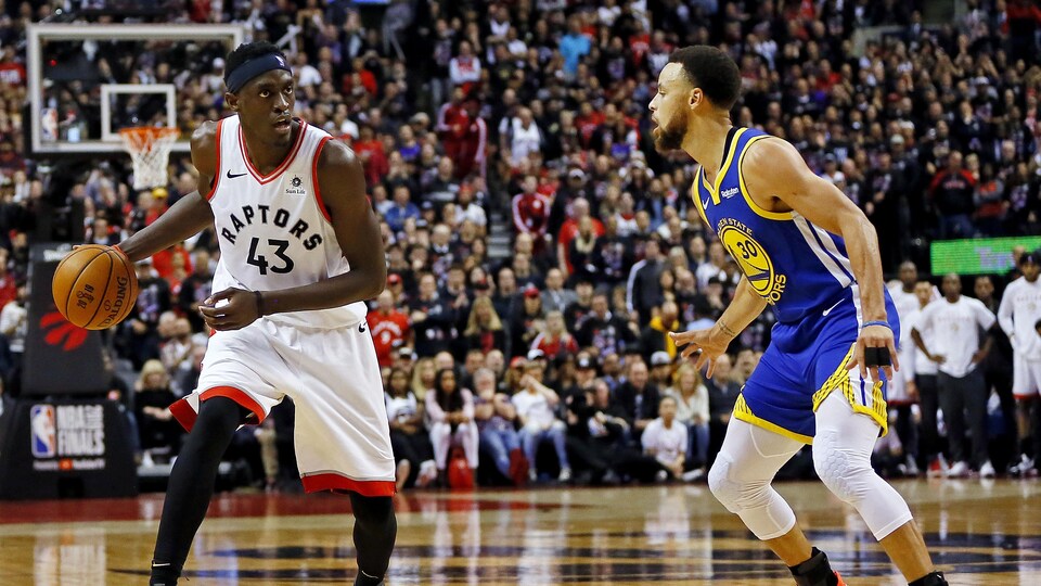 Pascal Siakam (à gauche) est surveillé par Stephen Curry.