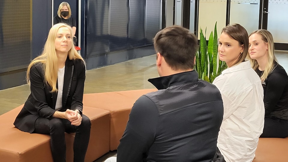 A woman is sitting and talking to three other people.