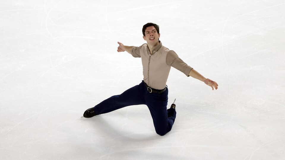 Un genou sur la glace, il étend les bras.