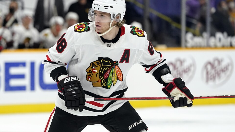 Patrick Kane dans son uniforme des Blackhawks de Chicago sur la glace son bâton dans les mains.