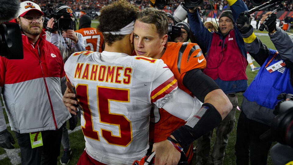 Les quarts-arrières Patrick Mahomes et Joe Burrow se serrent dans leurs bras sur un terrain de football.