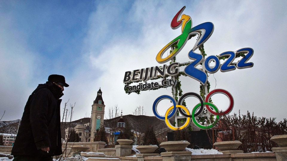 Un homme marche devant un logo de Pékin 2022.
