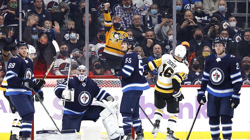 Un partisan des Penguins dans la foule manitobaine alors qu'un joueur de Pittsburgh célèbre un but.