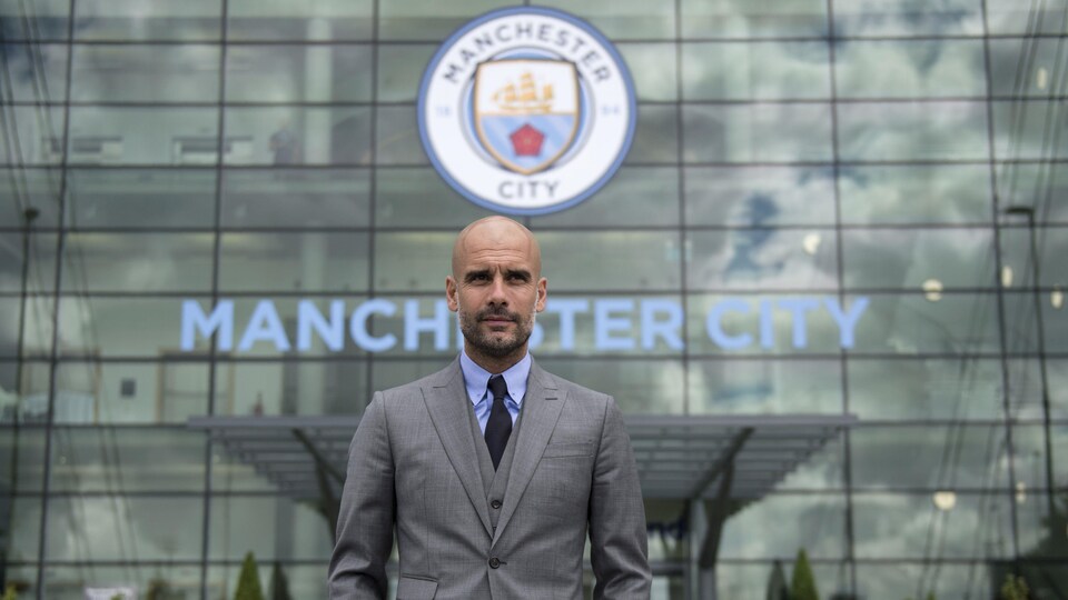 Il pose devant un immeuble frappé du logo de Manchester City.
