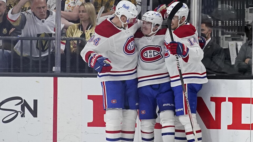 Trois joueurs de hockey s'étreignent.