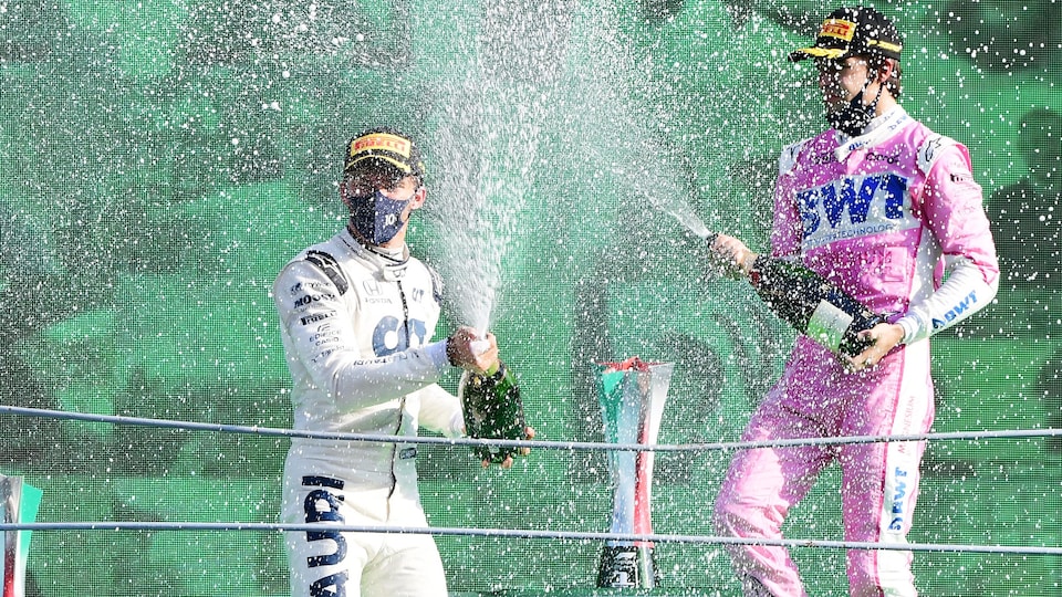 Deux pilotes sabrent le champagne sur le podium.