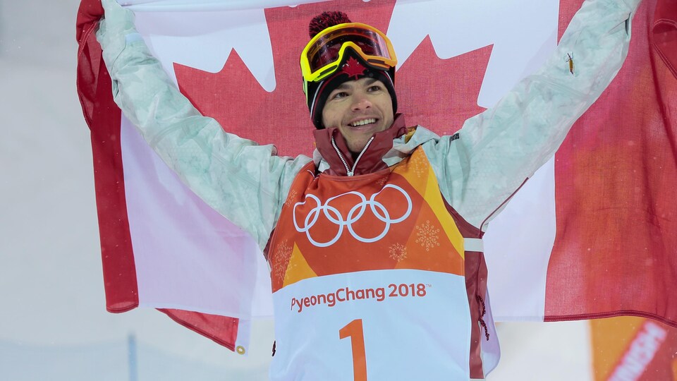Mikaël Kingsbury célèbre sa victoire avec un drapeau canadien