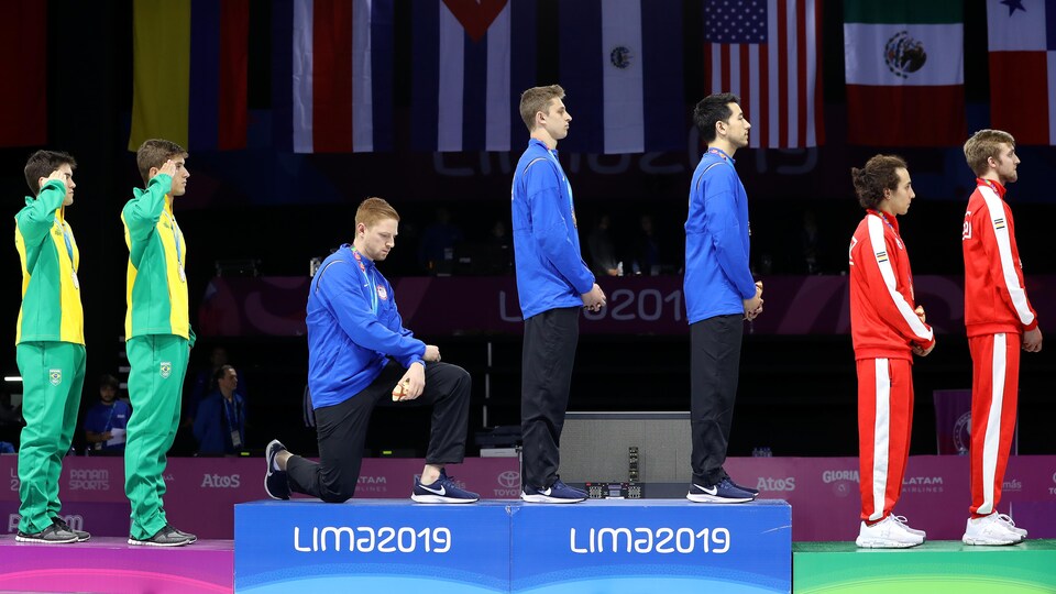 Il pose le genou droit sur le podium.