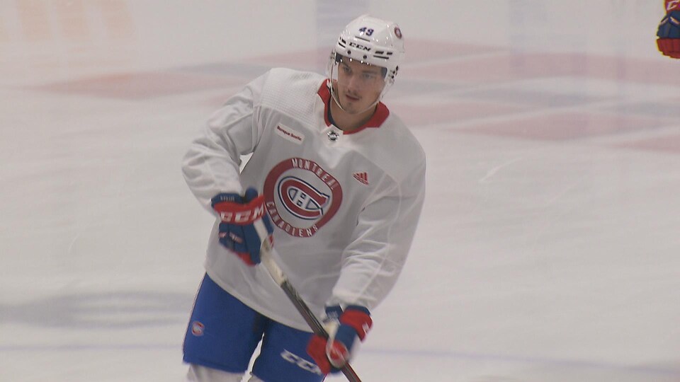 Le joueur de hockey, vêtu d'un uniforme blanc, surveille l'action sur la glace pendant le camp des recrues du Canadien.