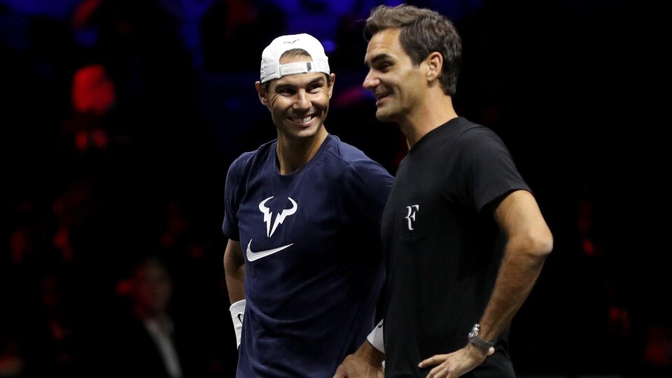 Les deux joueurs de tennis se regardent et sourient sur un terrain.