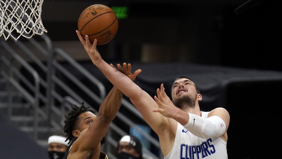 Il tente un panier pendant que Khem Birch, des Raptors, met une main sur son bras.