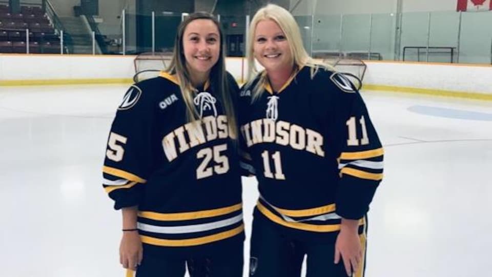 Deux joueuses de hockey posent sur la patinoire.