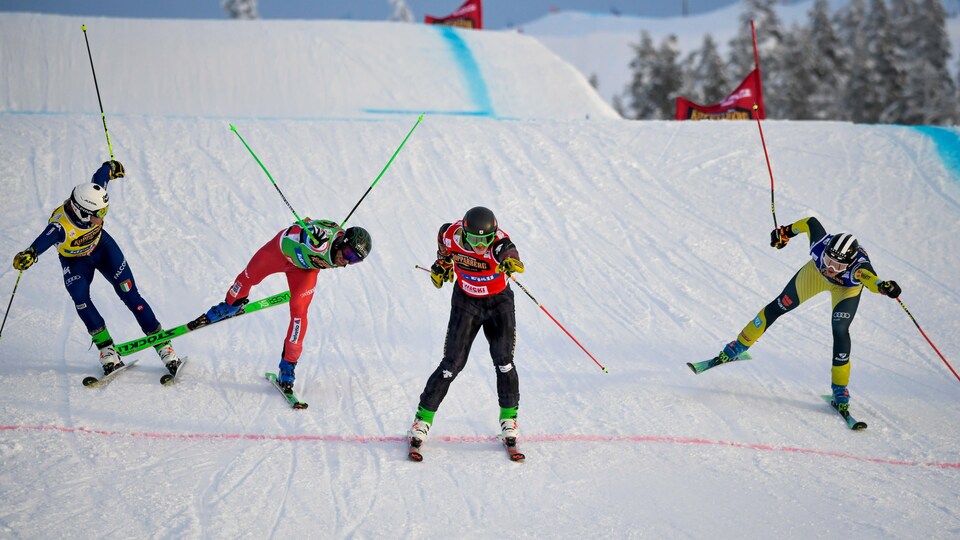 Quatre skieurs franchissent le fil d'arrivée.