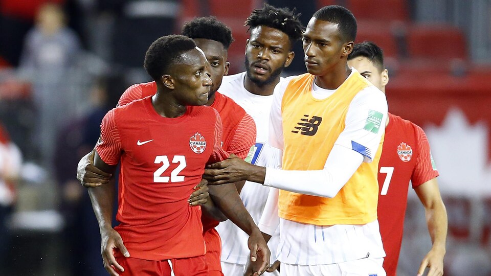 Le défenseur du Canada est retenu par son coéquipier Alphonso Davies et des joueurs du Panama, frustré par un incident sur le terrain.