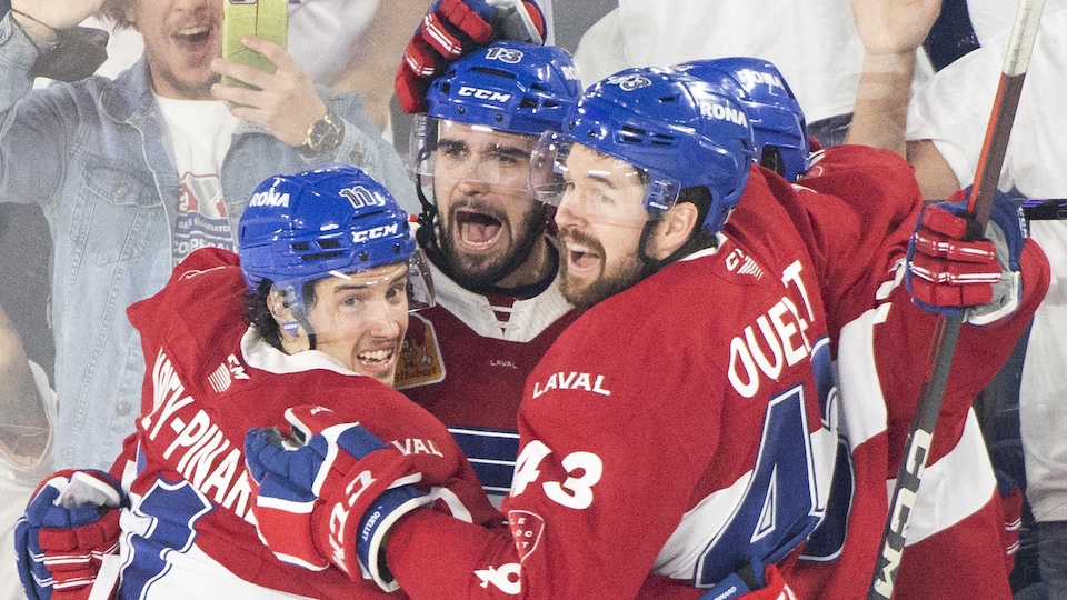 Quatre joueurs de hockey s'enlacent pour célébrer un but.