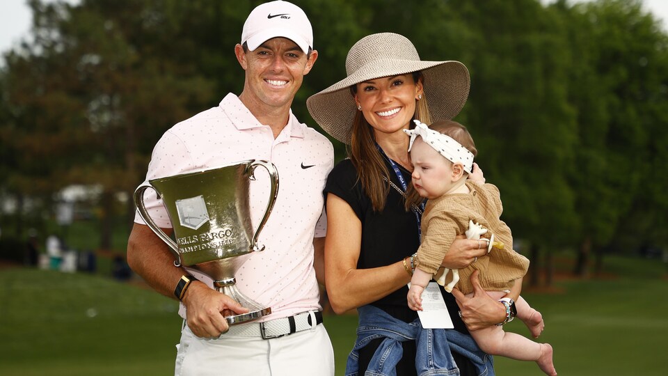 Il tient un trophée et sa femme leur bébé.