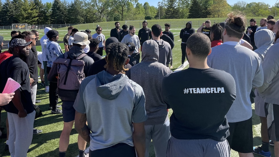 Football players chat on a pitch after practice.