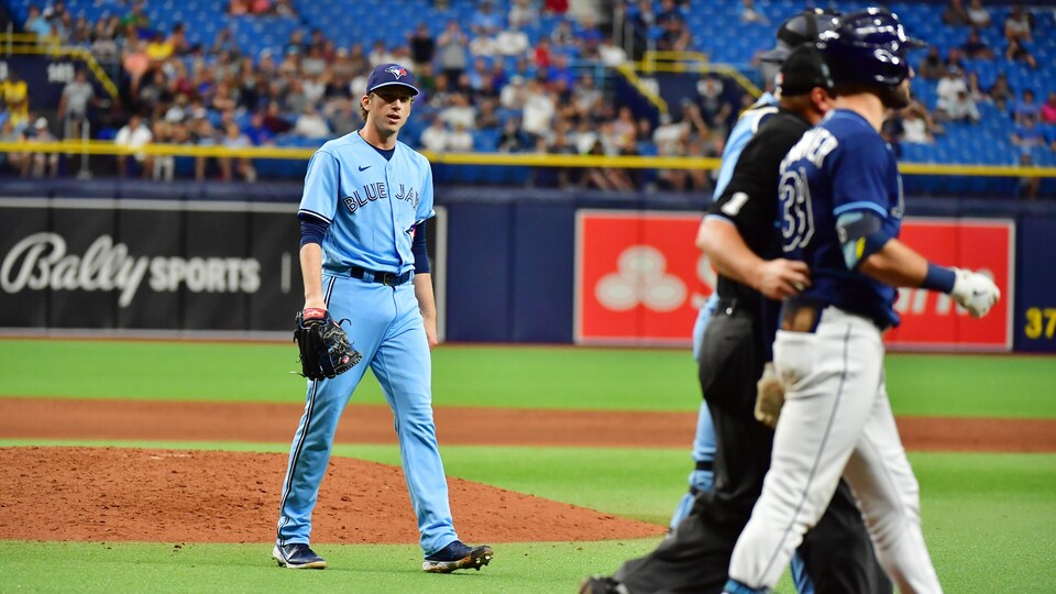 Le lanceur des Blue Jays quitte le monticule et marche vers Kiermaier, des Rays, escorté par un officiel.